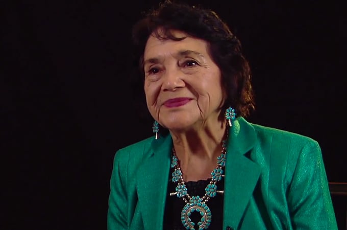 Civil rights activist and labor organizer Dolores Huerta smiles in a green outfit.