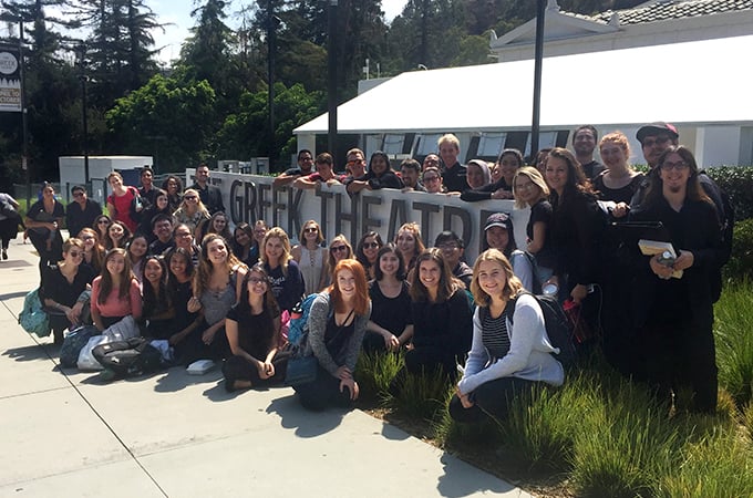 Members of Chapel Singers and Bel Canto choirs stand in front of the Greek Theater sign in L.A.