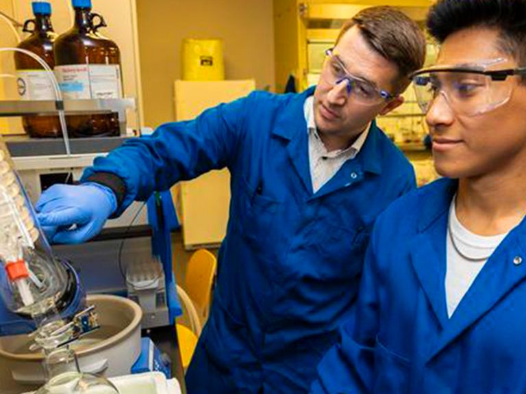 Professor teaching student in research science lab.