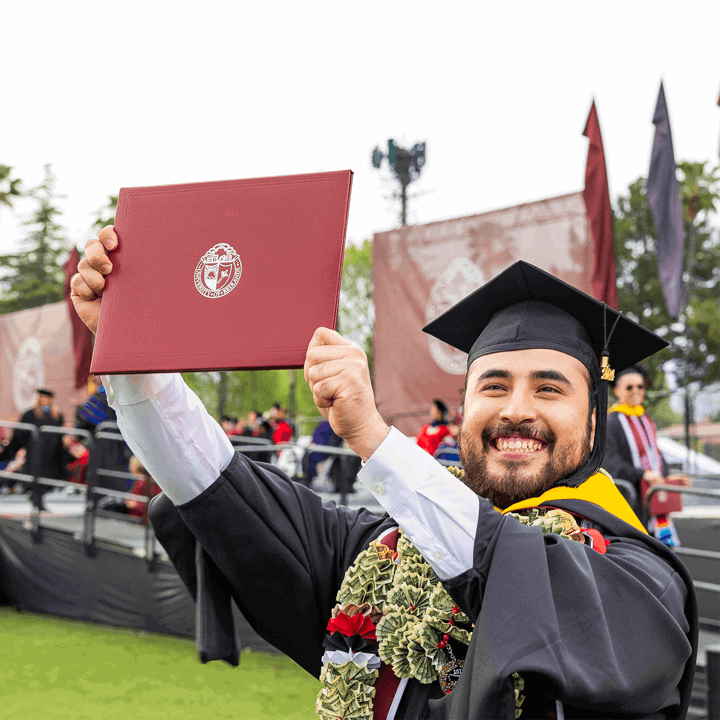 U of R Graduate proudly holding up diploma