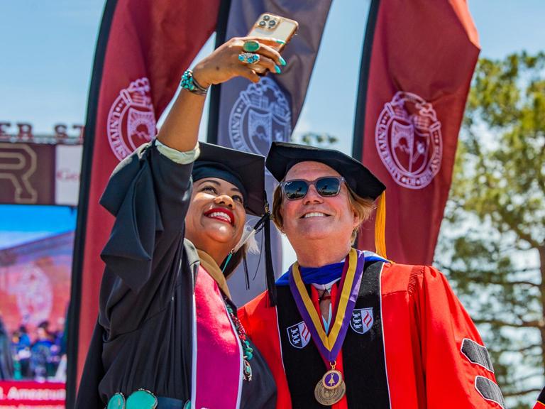 Image card - SBS graduate capturing selfie with Dean