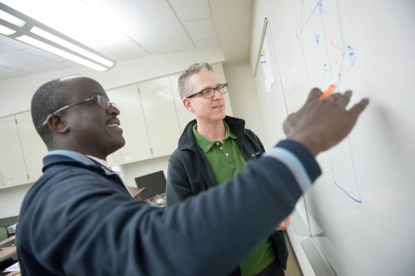 student and professor working on a whiteboard